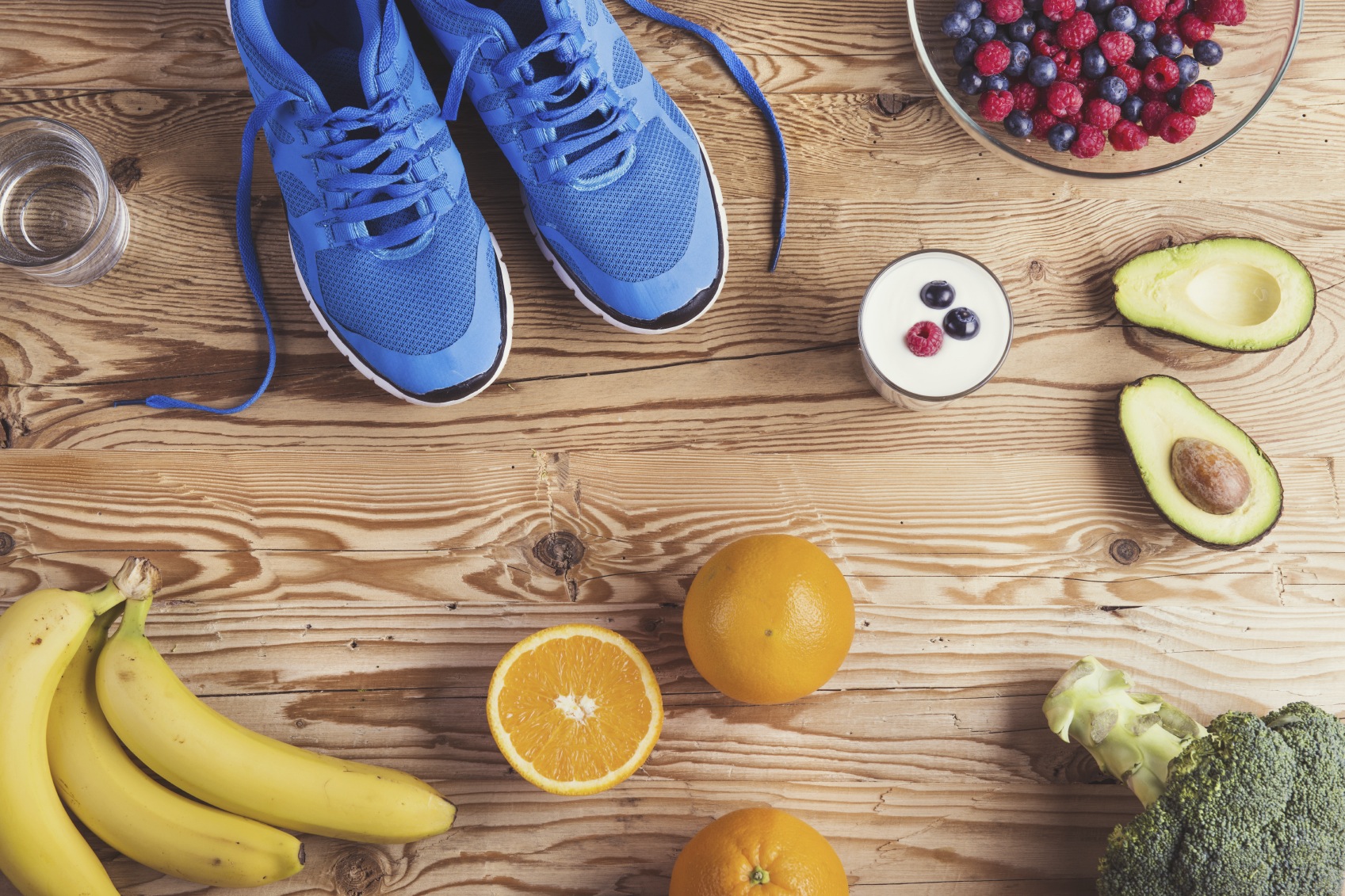 Pair of running shoes and healthy food composition on a wooden table background