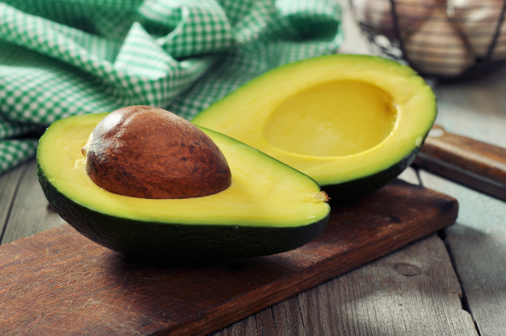 Fresh avocado on cutting board over wooden background