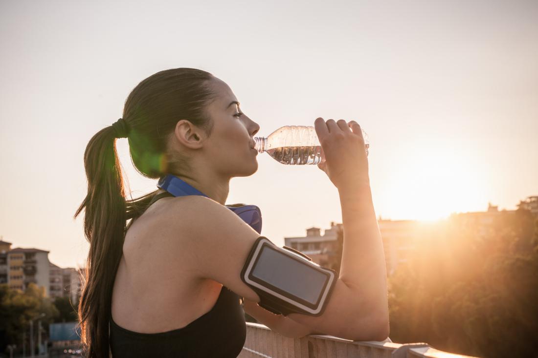 Young woman wearing armband drinking water